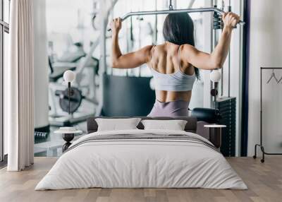 Fitness young woman working out in gym doing exercise for back. Athletic girl doing lat pulldown Wall mural